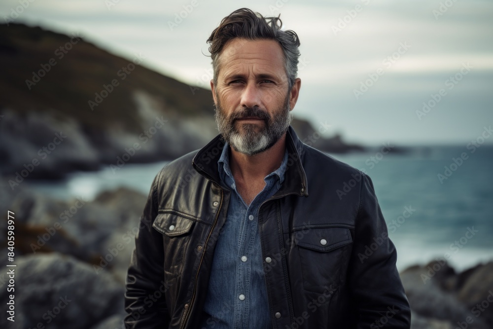 Portrait of a blissful man in his 40s sporting a stylish varsity jacket over rocky shoreline background Portrait of a blissful man in his 40s sporting a stylish varsity jacket over rocky shoreline background