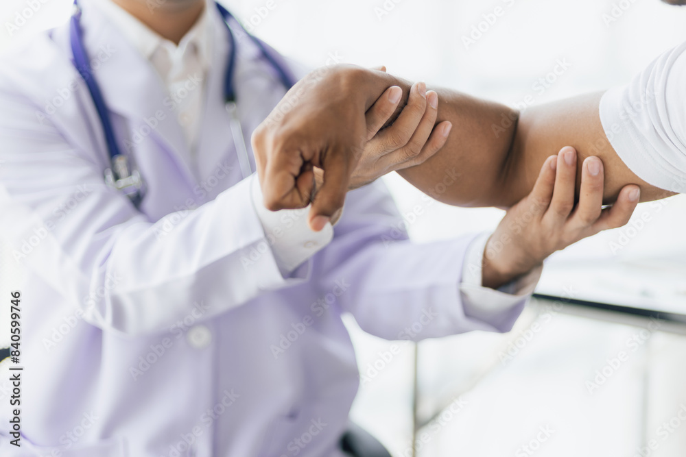 Man with arm pain, wrist pain and shoulder pain is seeing a doctor for diagnosis in an examination room at a hospital. Man with arm pain, wrist pain and shoulder pain is seeing a doctor for diagnosis in an examination room at a hospital.