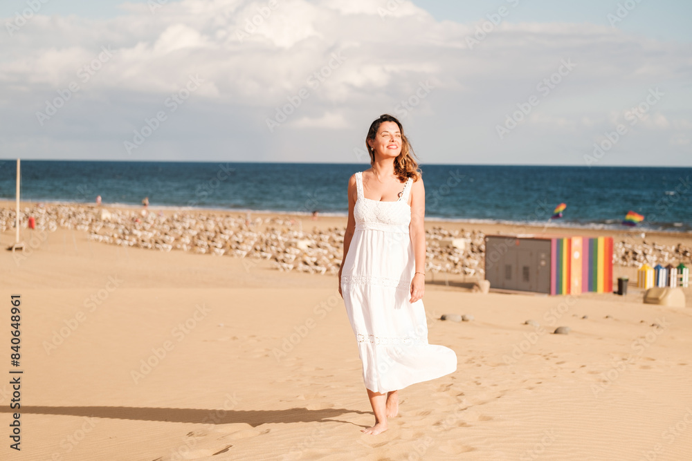 Middle-aged woman walking among the dunes with the LGBTI flags in the background. Concept: pride. Middle-aged woman walking among the dunes with the LGBTI flags in the background. Concept: pride.