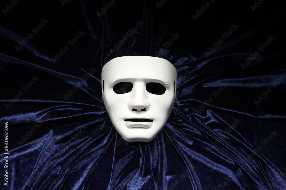Theater arts. White mask on blue fabric, top view Theater arts. White mask on blue fabric, top view