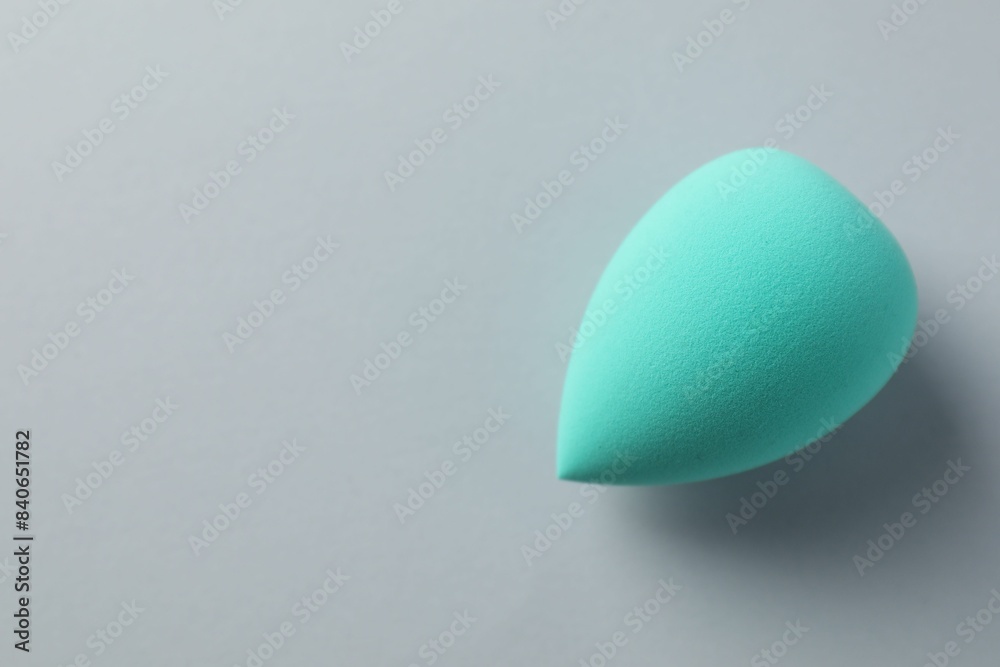 One turquoise makeup sponge on grey background, top view. Space for text One turquoise makeup sponge on grey background, top view. Space for text