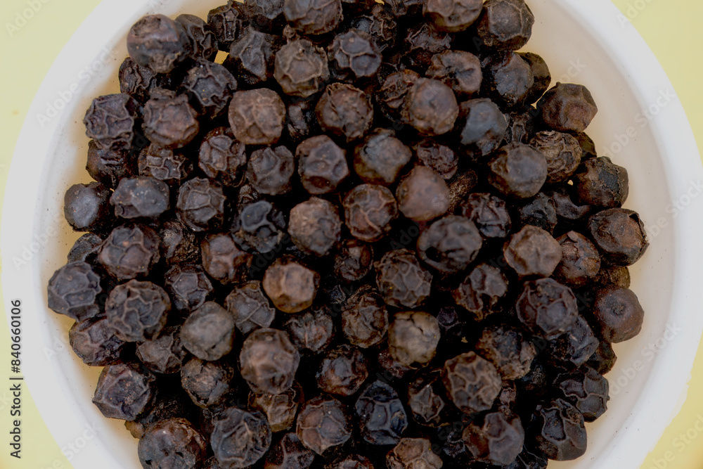 Top view of a heap of black pepper in a white bowl, captured in a close-up shot. Top view of a heap of black pepper in a white bowl, captured in a close-up shot.