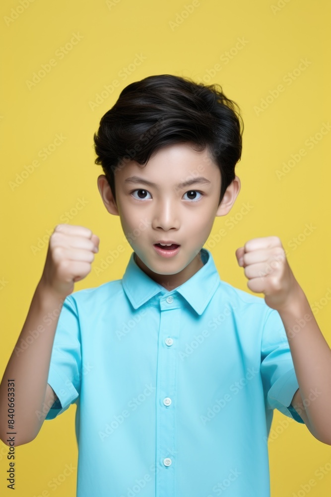 A young boy holding up his hand in a fist, possibly expressing determination or defiance A young boy holding up his hand in a fist, possibly expressing determination or defiance