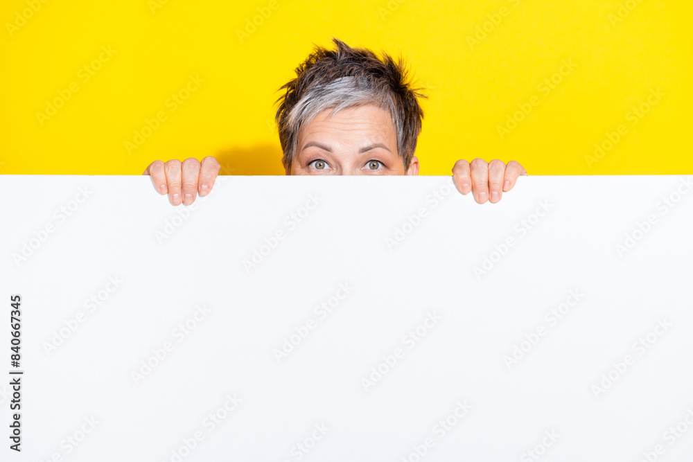 Photo of attractive retired woman hide behind empty space dressed stylish colorful clothes isolated on yellow color background Photo of attractive retired woman hide behind empty space dressed stylish colorful clothes isolated on yellow color background
