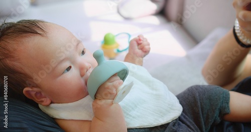 Obraz na plátně A close-up of a baby lying down and chewing on a blue teething toy looks content and focused