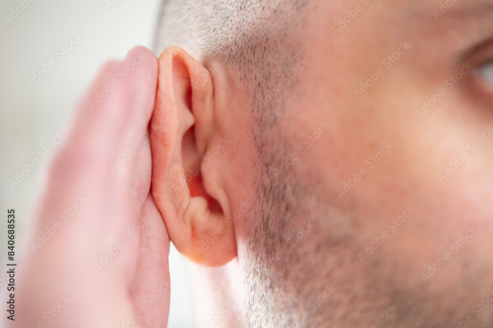 Fototapeta premium Young man clutches ear in pain, suffering from severe earache, hearing loss, Ear Discomfort, Hearing Test, Acute Otitis Media, Treatment and Care