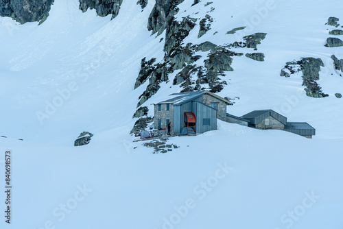 Mountain hut sitting at the bottom of rocky mountain covered in a snow in French alps near Grenoble