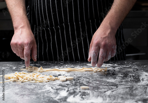 Close-up of the process of making homemade pasta. The chef prepares fresh traditional Italian pasta on a metal table. © Татьяна Качайло