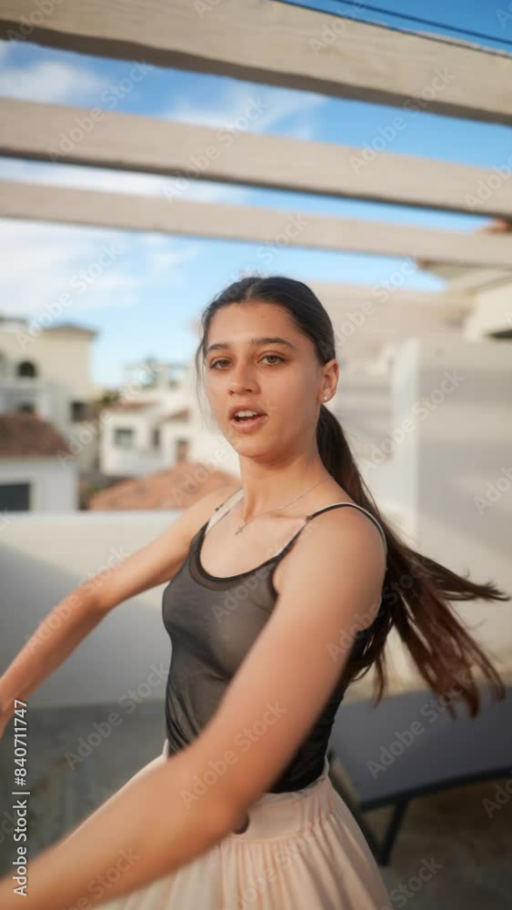 Young woman gracefully moving on a rooftop at sunset, the cityscape in the background Young woman gracefully moving on a rooftop at sunset, the cityscape in the background