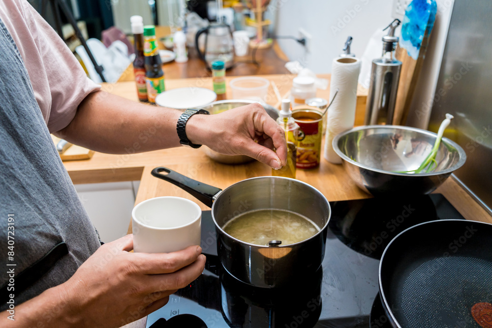 Chef at the kitchen preparing rice porridge with onion and sesame seeds