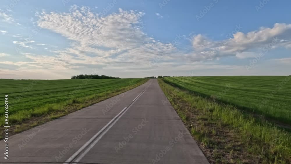 A car drives along the road on a summer day. Beautiful landscape, road markings, roadsides and road lines. A car drives along the road on a summer day. Beautiful landscape, road markings, roadsides and road lines.