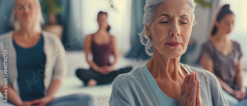Elderly woman meditating with closed eyes and hands in prayer position, capturing a moment of peaceful introspection.