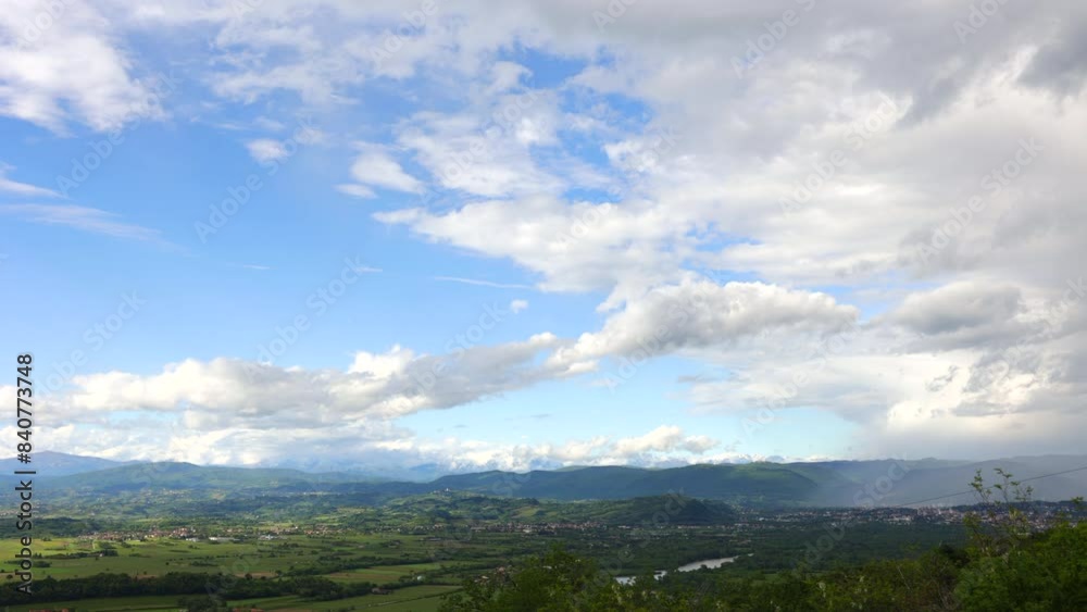 visuale dettagliata, da lontano e dall'alto, di un ambiente naturale del nord est Italia, di pomeriggio, in estate, mentre un temporale passa sopra la pianura e le colline