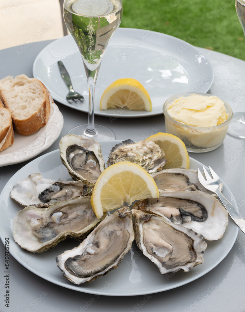 Champagne sparkling wine in glasses and oysters from Arcachon bay served on oysters farm in Gujan-Mestras, with lemon, baquette bread, butter Champagne sparkling wine in glasses and oysters from Arcachon bay served on oysters farm in Gujan-Mestras, with lemon, baquette bread, butter
