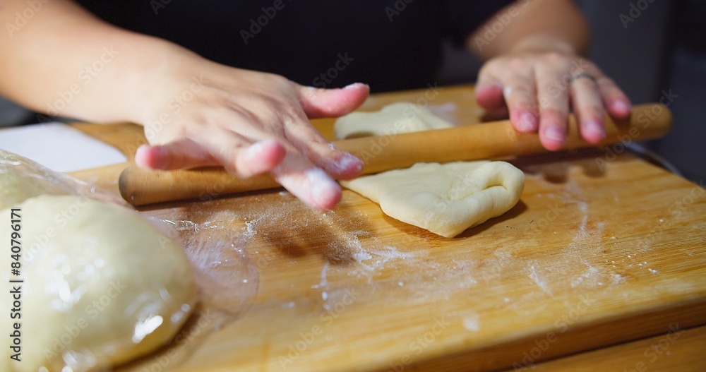 A woman is rolling out dough on a wooden table A woman is rolling out dough on a wooden table