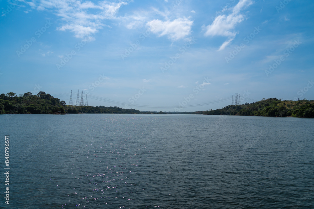Obraz premium High voltage lines and power tower on Xingu River near Belo Monte hydro power plant in Amazon rainforest in Altamira city, Para, Brazil. Concept of environment, ecology, nature, energy, electricity. 