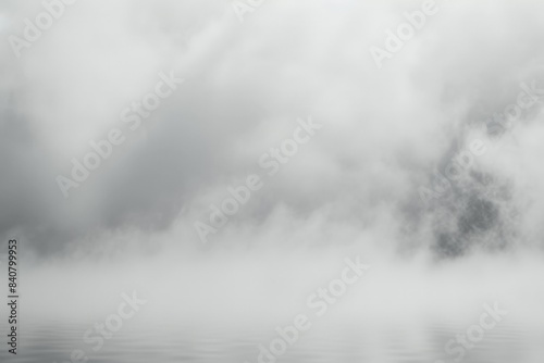 Dense fog is hovering over the water, creating a mysterious and captivating atmosphere. The sky above is filled with thick clouds, adding to the overall sense of drama and intrigue