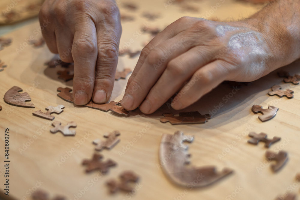 Dementia prevention. Elderly man hands doing jigsaw puzzle at home Dementia prevention. Elderly man hands doing jigsaw puzzle at home