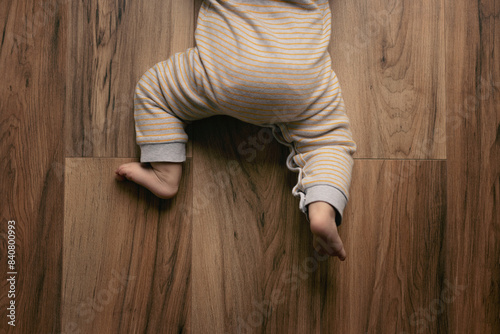 Closeup of barefoot baby feet on a wooden floor at home, view from above photo