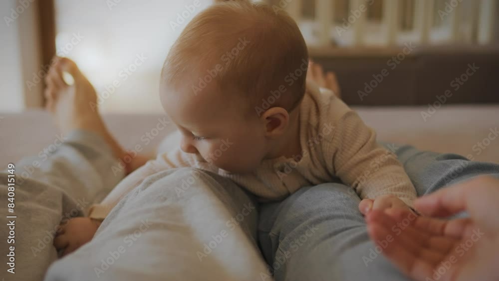 A married couple is sitting on a bed, with their child lying between them. The baby learns to crawl by actively moving his legs. On a clear day, a family relaxes on the sofa. Parents show their love