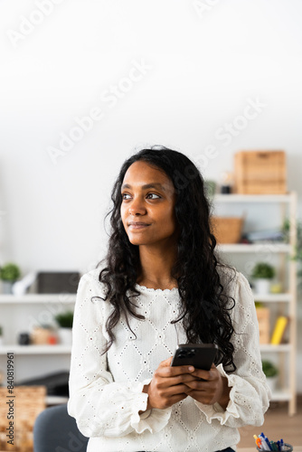 Pensive entrepreneur thinking while holding phone with copy space above.