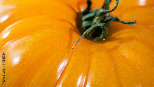 Vibrant and bright orange colored gourmet  tomato , covering the entire frame. Captured in a highly detailed close up. Green groceries and harvesting season concept.