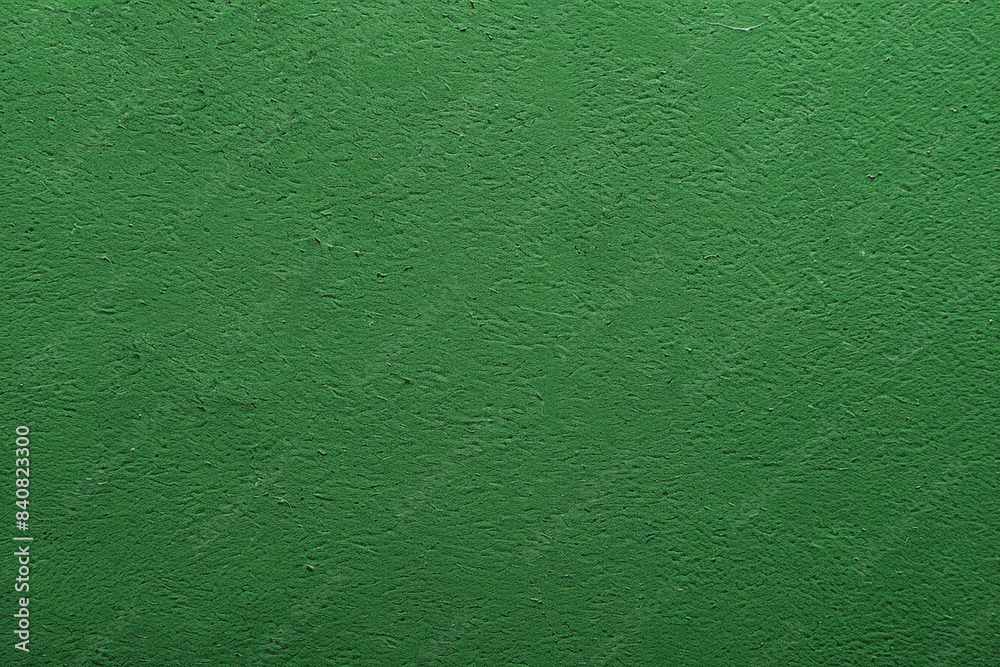 Fototapeta premium Textured background showing a rough concrete wall painted green, providing a bold and vibrant backdrop. This grunge-style image is perfect for adding a touch of urban edge to any project