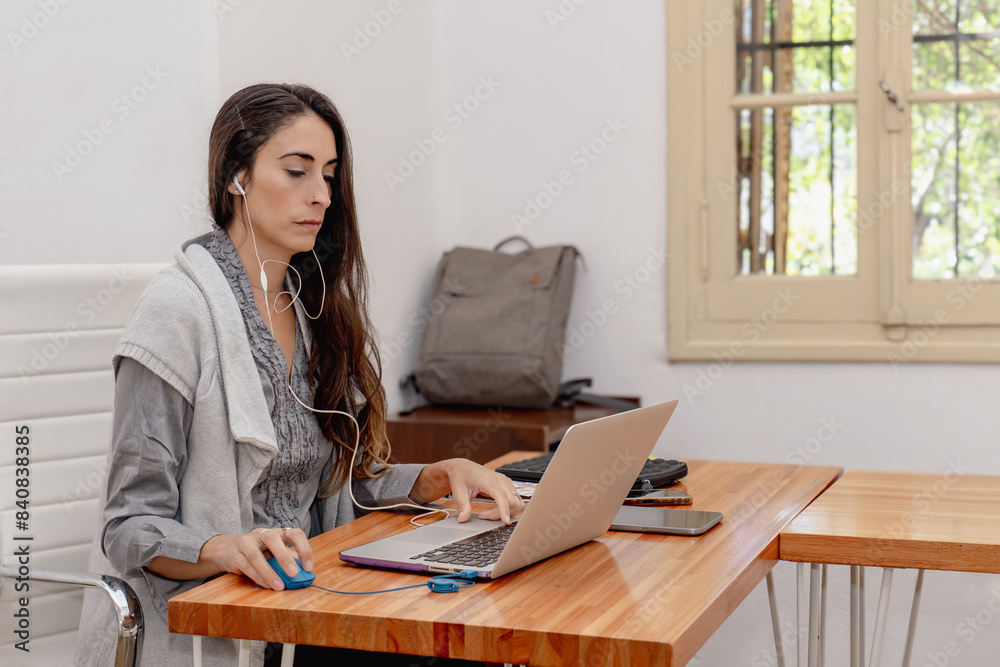 Woman working from home office desk with laptop and headset. Woman working from home office desk with laptop and headset.