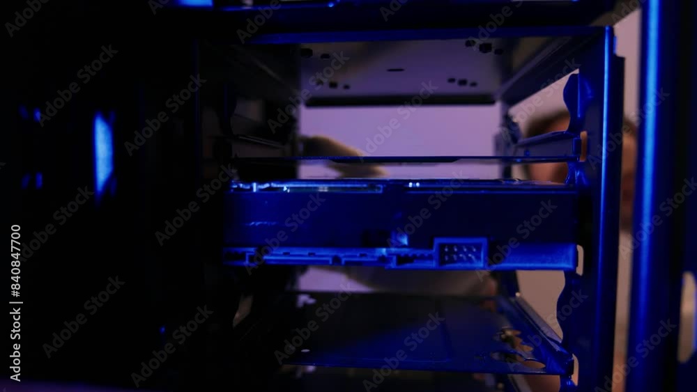 Computer technician installing hard disk close up in PC case. Assemble computer system unit to a modern workstation. Upgrading Rendering and gaming computer hardware components Computer technician installing hard disk close up in PC case. Assemble computer system unit to a modern workstation. Upgrading Rendering and gaming computer hardware components