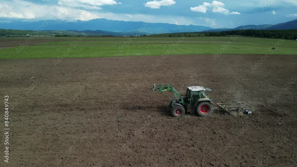 Drone view of tractor plowing field in cultivated land and soil tillage. Concept of work in agronomic farm for making business with organic food. Farmer is preparing field for new crops Drone view of tractor plowing field in cultivated land and soil tillage. Concept of work in agronomic farm for making business with organic food. Farmer is preparing field for new crops