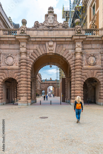 Photography A woman approaches the grand gates of the Swedish Parliament House, Riksdagshuset, located in Stockholm, capturing the essence of historic and political significance