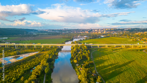 Aerial view of Lahovice Bridge spanning the Berounka River, with Prague cityscape in the distance during golden hour, casting warm light across the landscape. Prague, Czechia photo