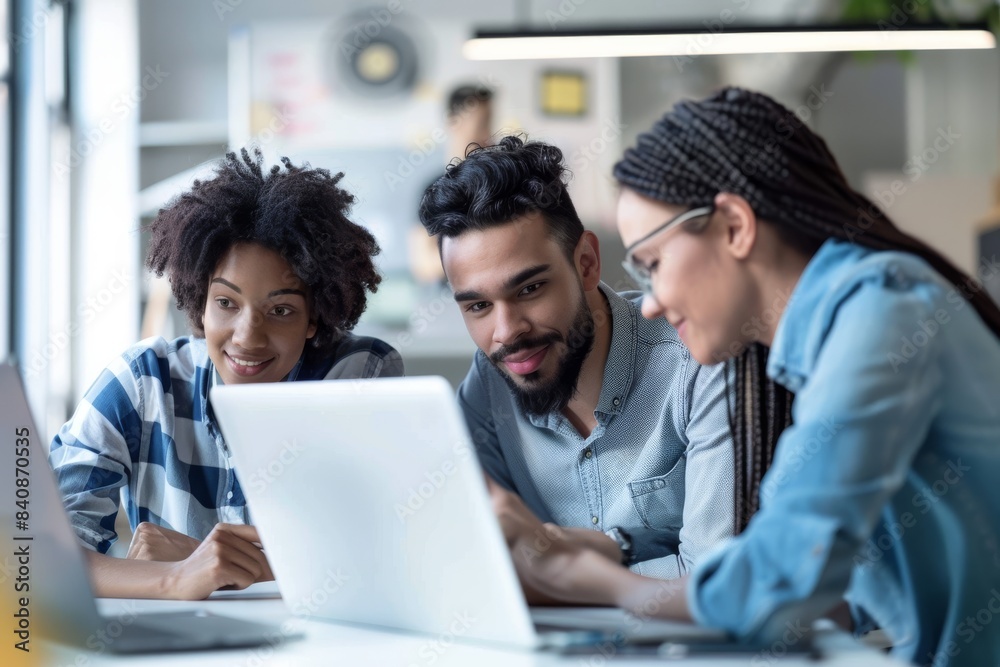 A Collaborative Moment: Three Professionals Huddle Over a Laptop in a Modern Office Space A Collaborative Moment: Three Professionals Huddle Over a Laptop in a Modern Office Space