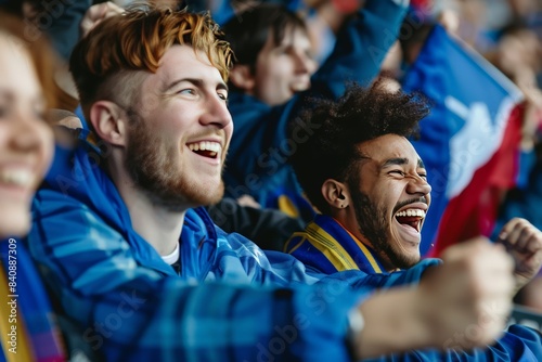 Fans in blue cheering ecstatically with raised scarves in a sports stadium photo