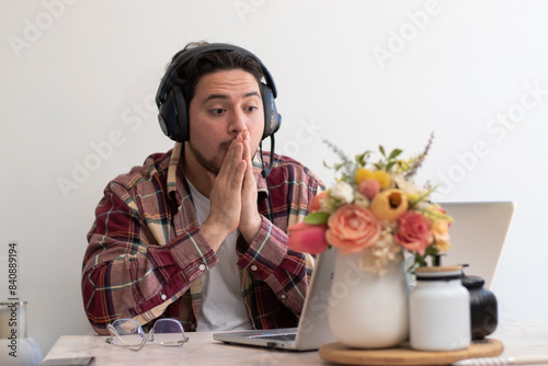 Gamer boy playing in his laptop in the living room with headset and getting emotions
