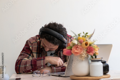 Young man with headache with his laptop in the living room making pain gesture