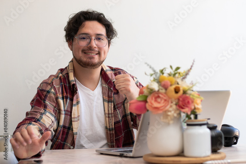 Young man with glasses from his laptop making gesture and wellness vibes concept in the living room
