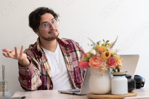 Young man with glasses from his laptop making gesture and wellness vibes concept in the living room