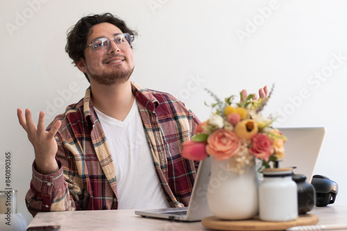 Young religious man in the living room with his laptop making thankfull gesture to the sky photo