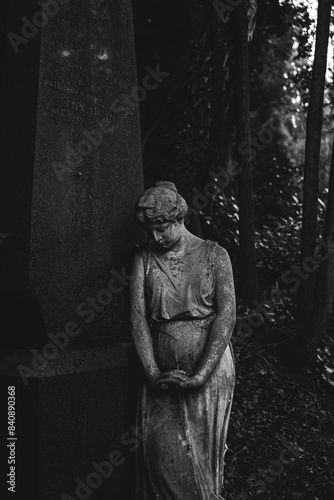 The weathered figure of a mourning woman adds a touch of solemn beauty to the secluded, moss-covered cemetery