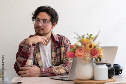 Young man with glasses from his laptop making gesture and wellness vibes concept in the living room