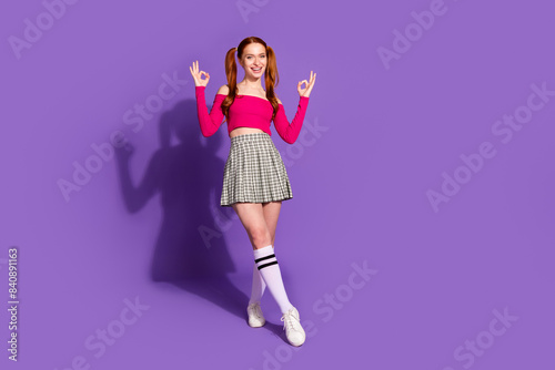 Full body photo of pretty young girl posing show okey wear trendy pink outfit isolated on purple color background