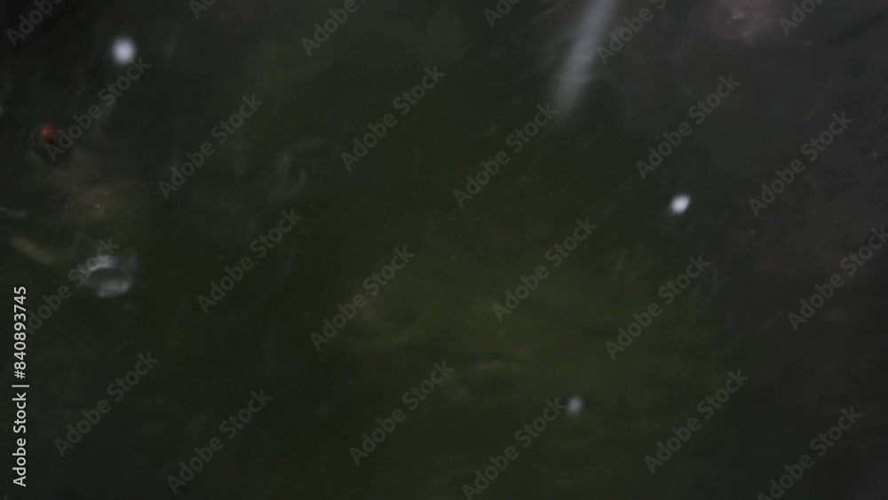 ripresa macro dell'acqua che scorre copiosa mentre piccoli chicchi di grandine colpiscono un vetro trasparente durante un temporale. sfondo sfuocato e color grigio scuro ripresa macro dell'acqua che scorre copiosa mentre piccoli chicchi di grandine colpiscono un vetro trasparente durante un temporale. sfondo sfuocato e color grigio scuro
