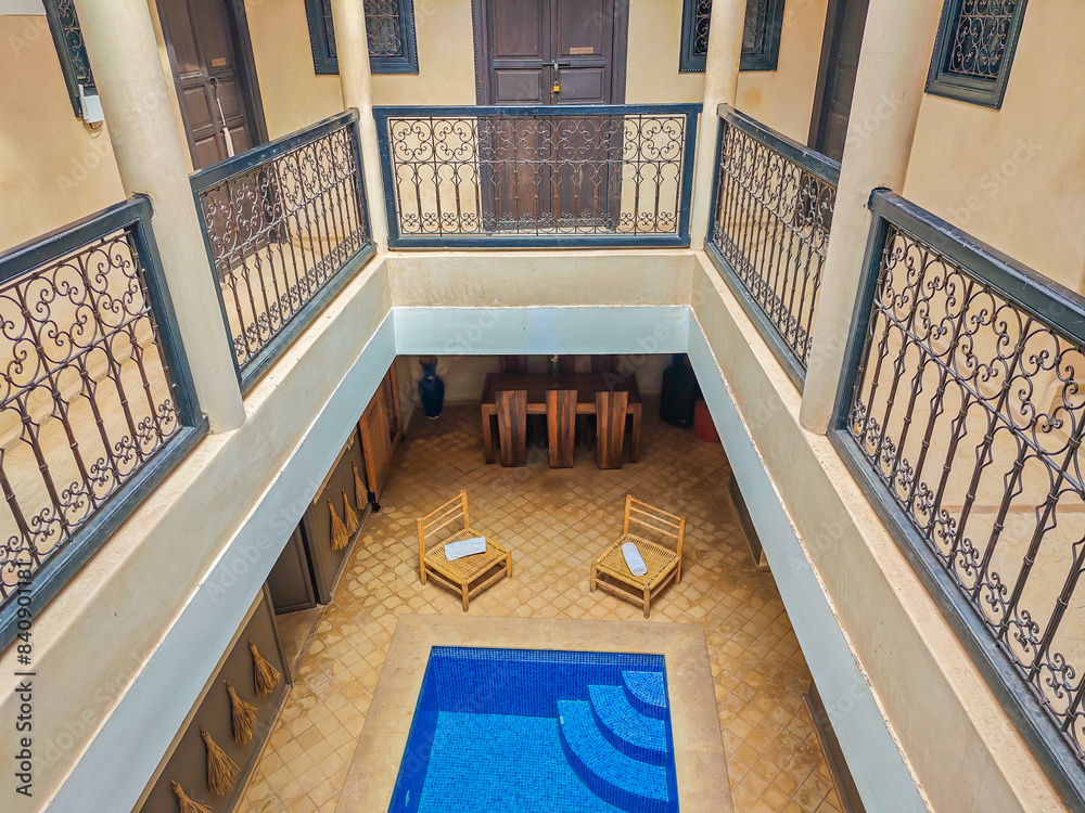 Obraz premium Interior of a typical Moroccan riad with a small pool in the middle of the building. Accommodation in traditional Moroccan hotel in Medina