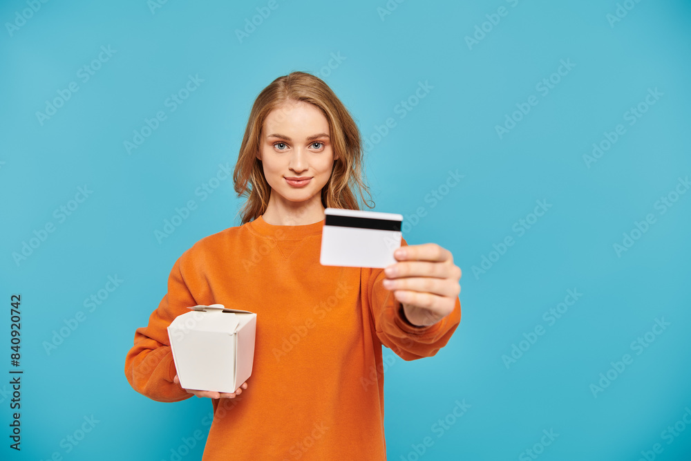 Stylish woman holding a credit card and a box of Asian food.