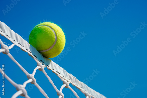 Tennis ball on the net tape with uncertainty on which side it will fall. photo