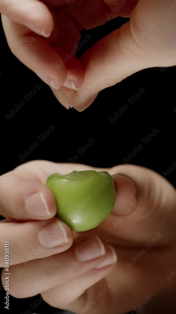 Vertical video. Woman Sprinkles Salt on Green Cherry Plums and Bites into Them, Creatively Enjoying Unripe Fruits. Vertical video. Woman Sprinkles Salt on Green Cherry Plums and Bites into Them, Creatively Enjoying Unripe Fruits.