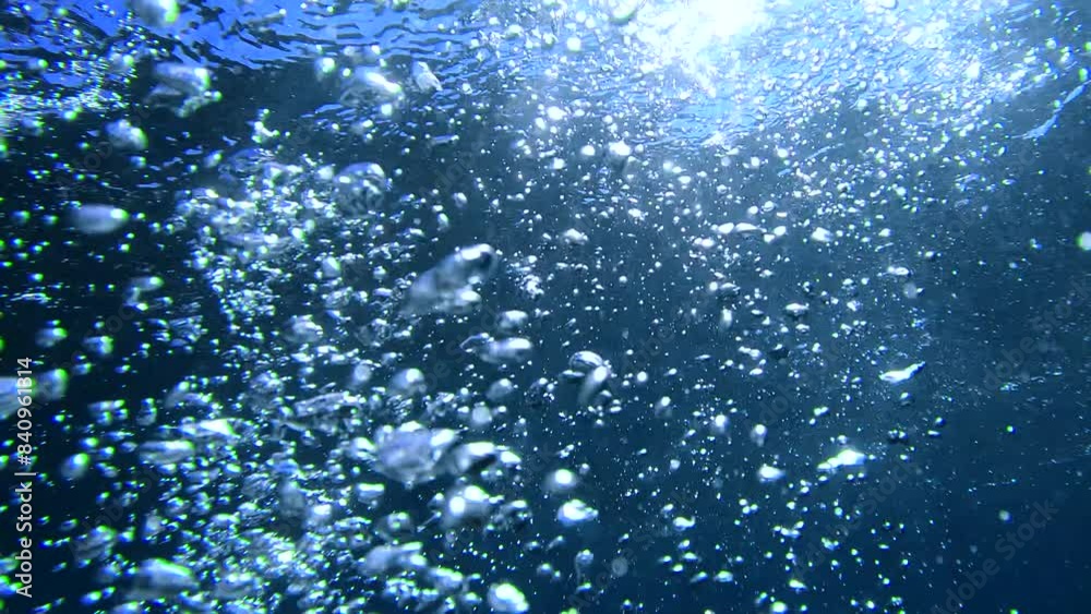 Underwater air Bubbles with sunlight through water surface, natural slow motion under water scene. Air bubbles floating from  the sea bottom up to  water surface
