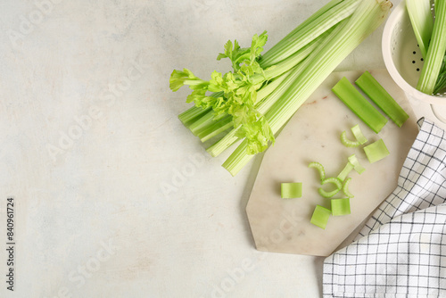 Board and colander with fresh green celery on white background