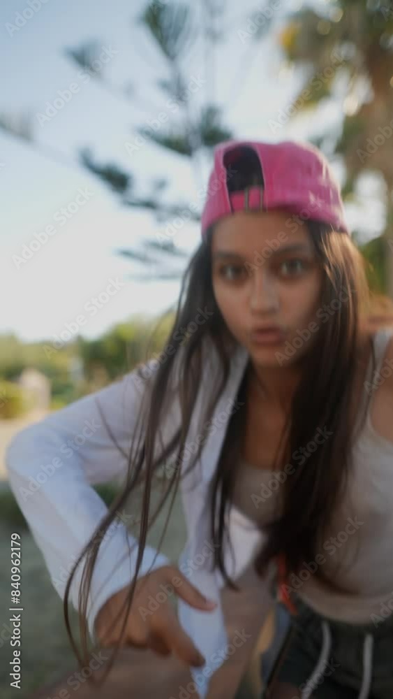Stylish teenager with long hair, wearing a pink cap, having fun outdoors under sunlight
